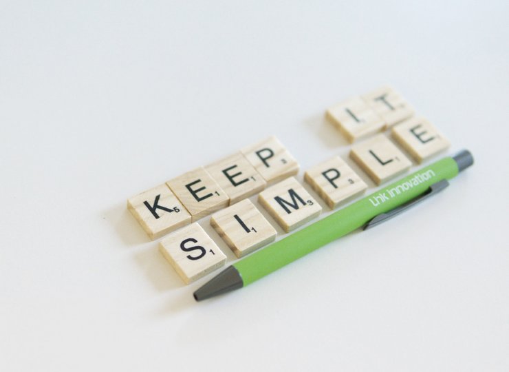 Das Motto "Keep it simple" auf Holzplättchen, darunter ein Kugelschreiber der Link Innovation GmbH.